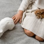 A child petting rabbits indoors on a patterned blanket, creating a warm, cozy atmosphere.