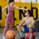 A couple sharing a moment in a gym setting with medicine balls, expressing fitness and togetherness.