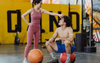 A couple sharing a moment in a gym setting with medicine balls, expressing fitness and togetherness.